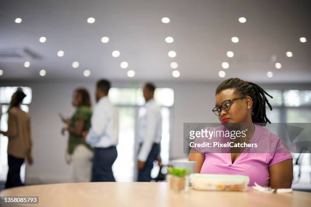 同僚が一緒に昼食に出かける間、若い女性は一人で座っている - 仲間はずれ ストックフォトと画像