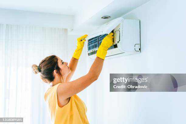 woman cleaning air conditioning system stock photo - ac repair stockfoto's en -beelden