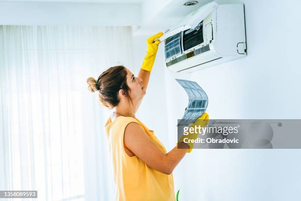 woman cleaning air conditioning system stock photo - broken air conditioner stock pictures, royalty-free photos & images