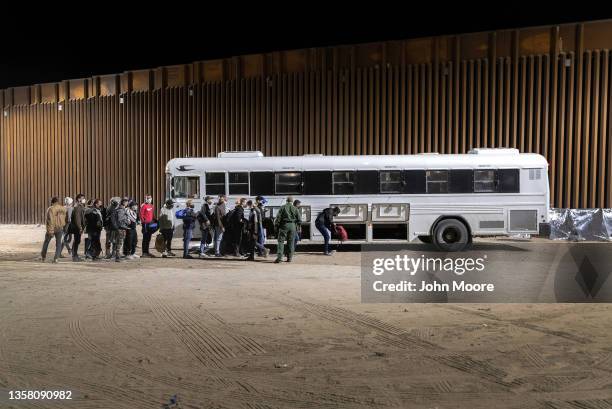 Border Patrol agents load immigrants into a bus for transport to a detention facility on December 08, 2021 through the city of Yuma, Arizona....