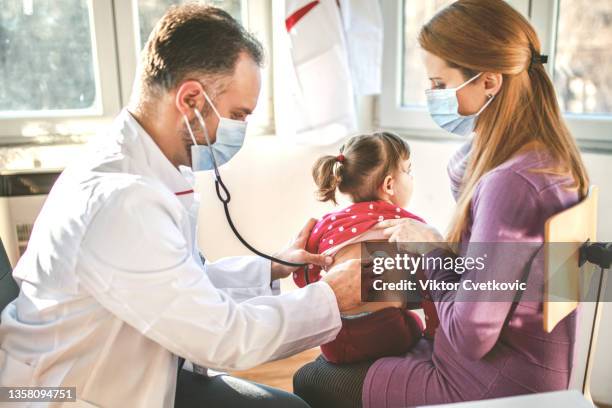 kinderarzt, der die lungen und die atmung des kleinen mädchens überprüft - respiratory disease stock-fotos und bilder