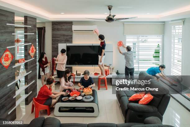 aisan chinesische familie schmückt ihren wohnsaal während des chinesischen silvesterabends - chinese new year home stock-fotos und bilder
