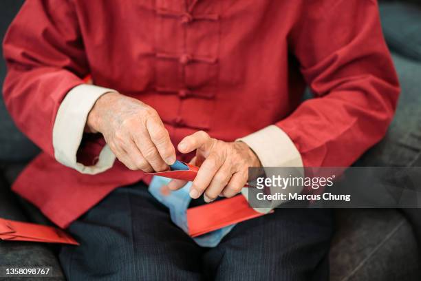 asian chinese senior men putting money into red envelope at living hall during chinese new year - chinese money stockfoto's en -beelden