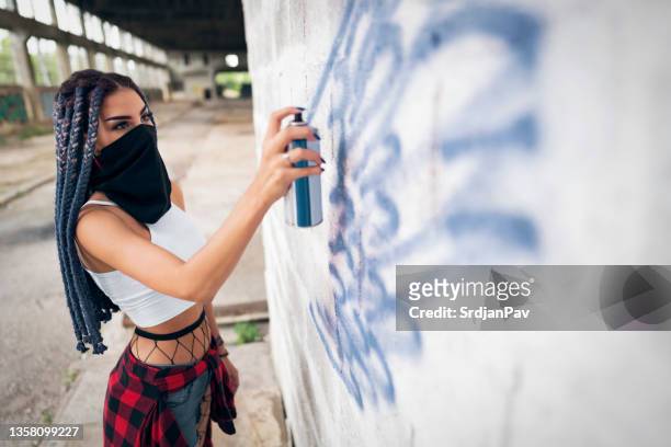 urban young caucasian woman drawing graffiti on the wall of an abandoned industrial buildin - purple bandanna stock pictures, royalty-free photos & images