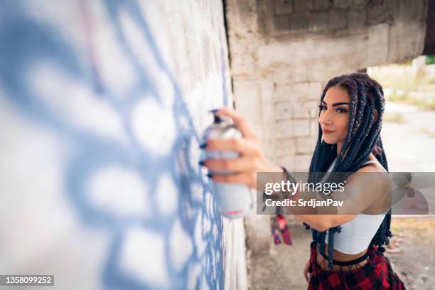 mulher jovem hipster caucasiana desenhando grafite na parede do prédio industrial - street artist - fotografias e filmes do acervo