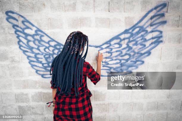 unrecognizable hipster woman, drawing with spray graffiti on the wall - street artist stock pictures, royalty-free photos & images