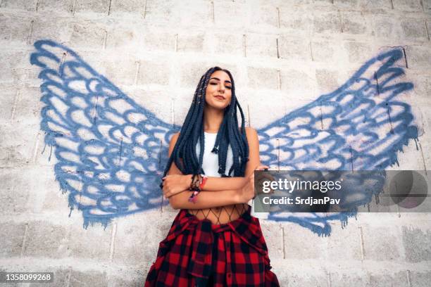 rebel caucasian woman, standing in front of the angel wings graffiti - street artist stock pictures, royalty-free photos & images