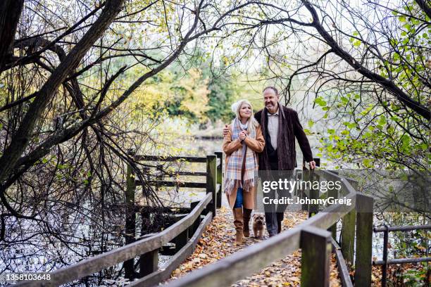 cheerful couple with dog returning from lake view - approaching stock pictures, royalty-free photos & images