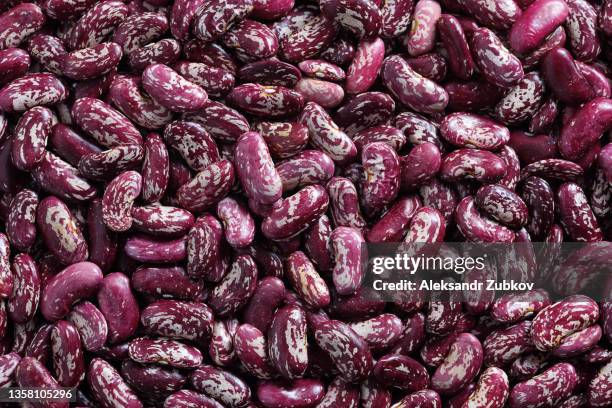 dried red beans are scattered on the kitchen table. vegetarian and vegan food. food textured background. - red beans stock pictures, royalty-free photos & images