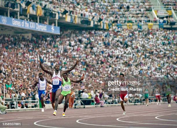 Carl Lewis of the United States raises his arms in celebration as he crosses the finish line to win the anchor leg of the Men's 4 x 100 relay metres...