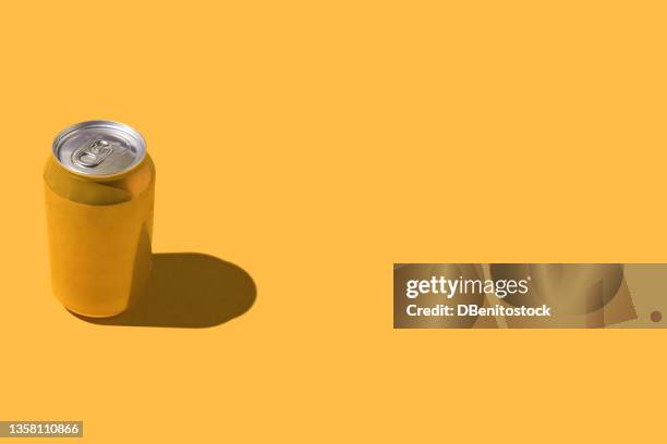 yellow soda beer can with hard shadow, on the left side, on red background. - carbonated water stock pictures, royalty-free photos & images