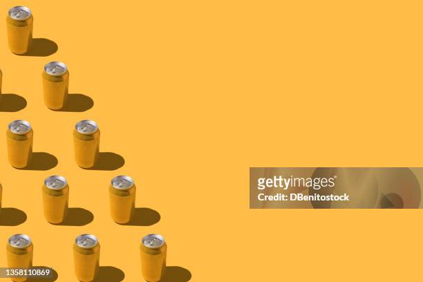 yellow soda beer cans pattern with hard shadow, on the left side, on red background. - hard liquor stock pictures, royalty-free photos & images