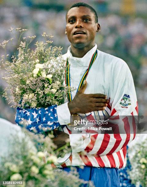 Carl Lewis of the United States sings the national anthem after winning the gold medal in the Men's Long Jump competition on 6th August 1992 during...