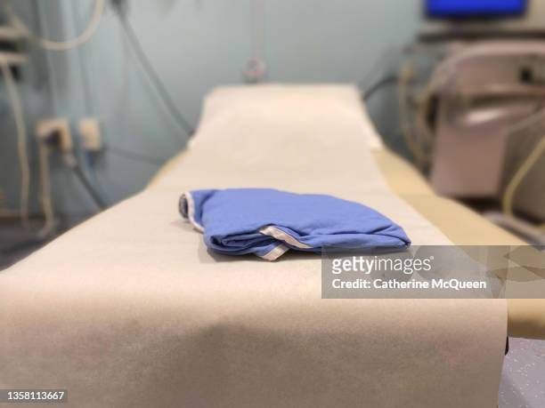 generic medical examination table & patient gown - hospital gown stock photos et images de collection
