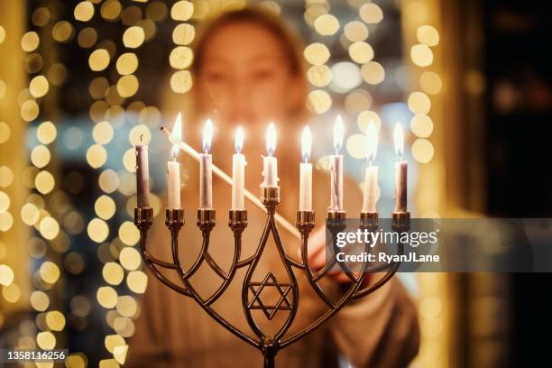 girl lighting menorah for hanukkah - chanoeka stockfoto's en -beelden