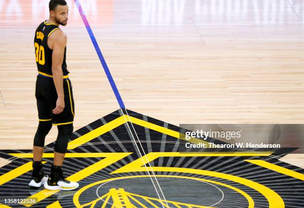 Stephen Curry of the Golden State Warriors standing on the 75th anniversary logo looks on from half court against the Portland Trail Blazers during...