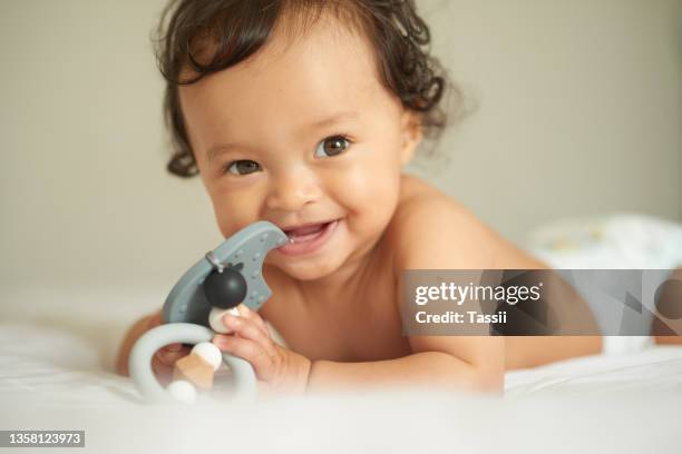 shot of an adorable baby girl playing with a teething rattle at home - mascar imagens e fotografias de stock