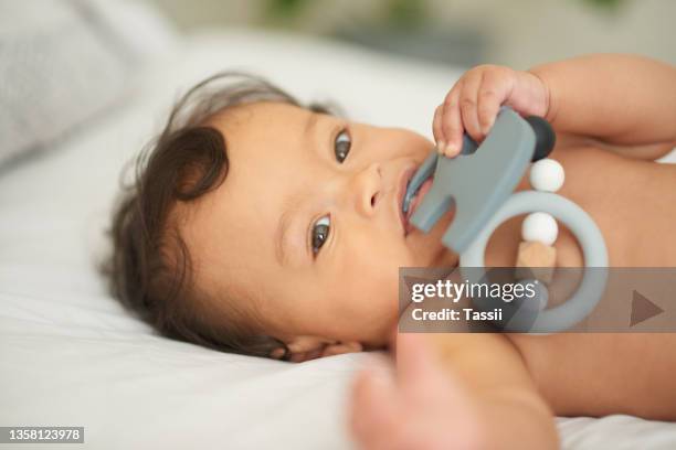 portrait of an adorable baby girl playing with a teething rattle at home - baby rattle stock pictures, royalty-free photos & images