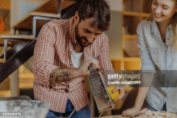 couple making pizza - grater stock pictures, royalty-free photos & images