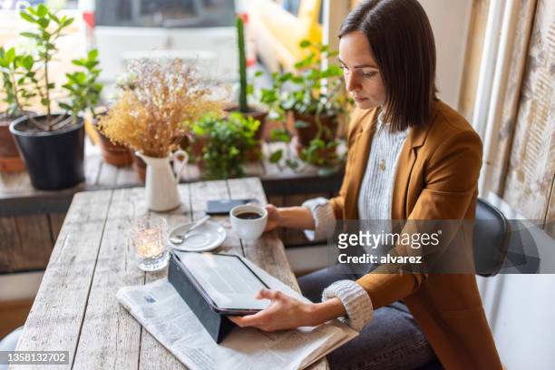 geschäftsfrau sitzt mit einem digitalen tablet in einem café - reading stock-fotos und bilder