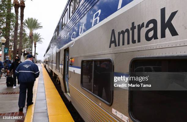 An Amtrak worker walks next to an Amtrak train during a station stop on December 9, 2021 in Fullerton, California. Amtrak is having difficulty hiring...