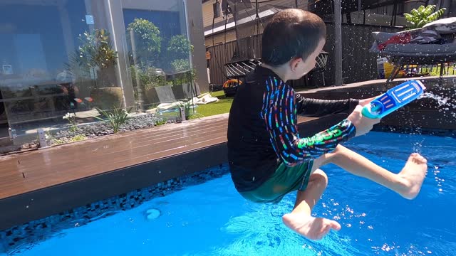 한 소년이 수영장으로 다이빙을 스핀한 다음 풍선 수영장 장난감을 통해 다이빙을 포함하여 POV 물 싸움을 합니다. 빠르게 진행되는 플레이.