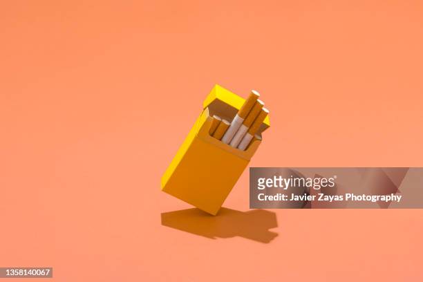 yellow cigarette pack on coral colored background - cigarette pack stock pictures, royalty-free photos & images