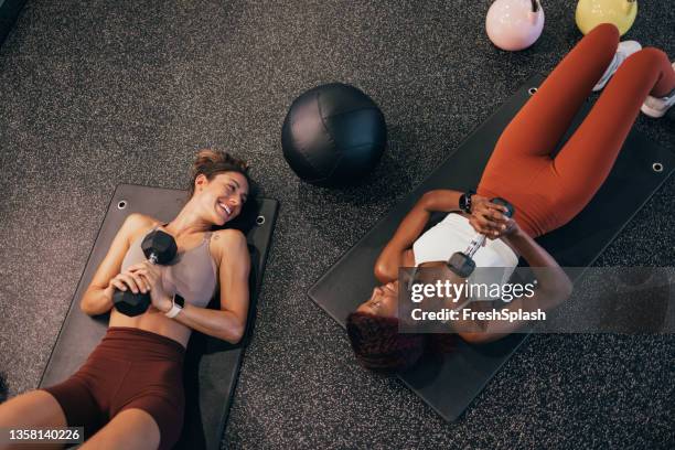 dos hermosas deportistas haciendo ejercicio en una colchoneta en el gimnasio - mancuerna fotografías e imágenes de stock