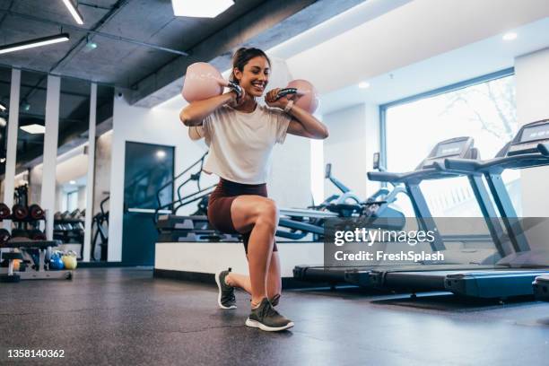 beautiful motivated fit woman working out using kettlebells at the gym - kettlebell stockfoto's en -beelden