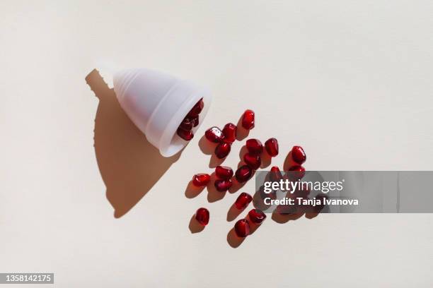 pomegranate seeds pour out of the menstrual cup - tampon menstruation stock-fotos und bilder