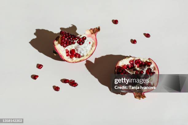 pomegranate and pomegranate seeds on grey background - juicy stock pictures, royalty-free photos & images