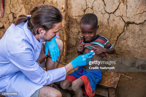 doctor examining young african boy in small village, kenya - third world stock pictures, royalty-free photos & images