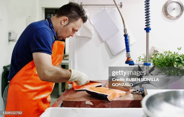 fishmonger wearing an orange apron filleting a salmon at fish market - fish vendor bildbanksfoton och bilder