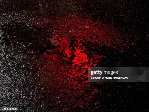 red color of city light reflecting on wet asphalt - nass stock-fotos und bilder