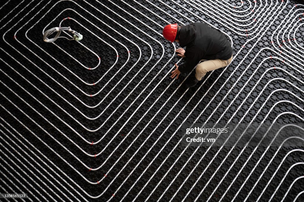 Worker adjusting position of pipes, diagonally oriented pattern on tubes