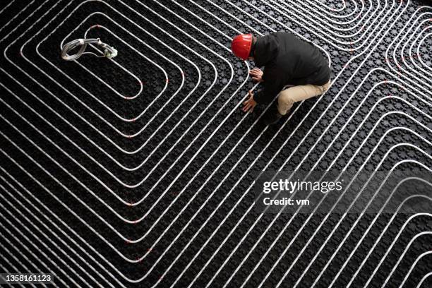 worker adjusting position of pipes, diagonally oriented pattern on tubes - flooring stock pictures, royalty-free photos & images
