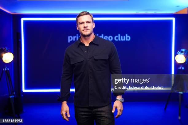 Alan Ritchson wears a black shirt, a Rolex watch, black jeans, during the inauguration Of The Prime Video Club at Place de La Madeleine, on December...