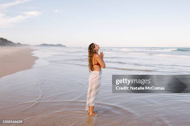 young grateful woman at a the beach in the daytime - byron bay stock-fotos und bilder