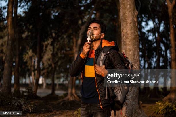 a man breathing oxygen while wearing a mask from trees in forest. - breathing device stock pictures, royalty-free photos & images