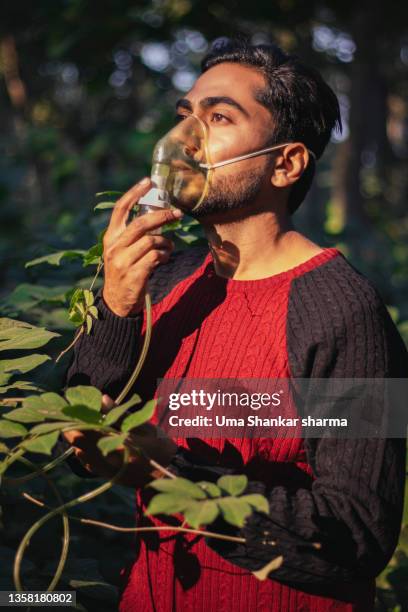 a man breathing oxygen while wearing a mask from trees in forest. - oxygen stock pictures, royalty-free photos & images