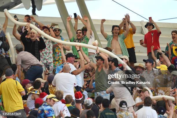 The crowd cheer as they make a beer cup snake during day three of the First Test Match in the Ashes series between Australia and England at The Gabba...