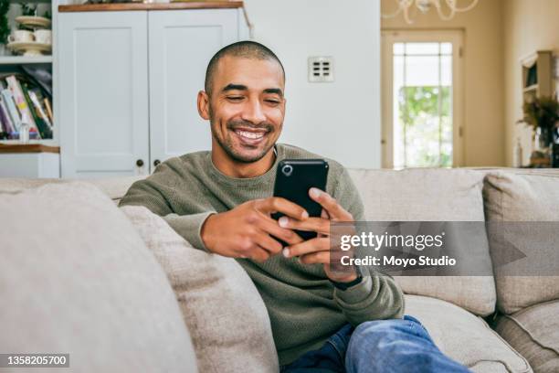 aufnahme eines jungen mannes, der sein smartphone benutzt, um textnachrichten zu senden - smiling stock-fotos und bilder