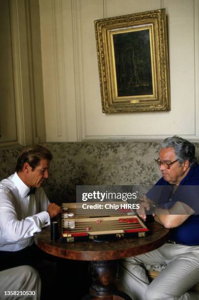 Roger Moore et le producteur Albert Broccoli jouent au backgammon pendant une pause du tournage du James Bond "Dangereusement vôtre", le 16 août 1984.