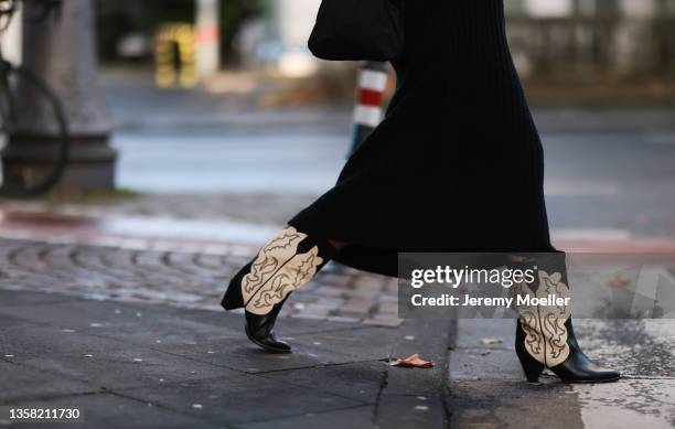 Henni wearing Isabel Marant Cowboy boots, Vival black knit dress and black Prada Nylon bag on December 07, 2021 in Cologne, Germany.