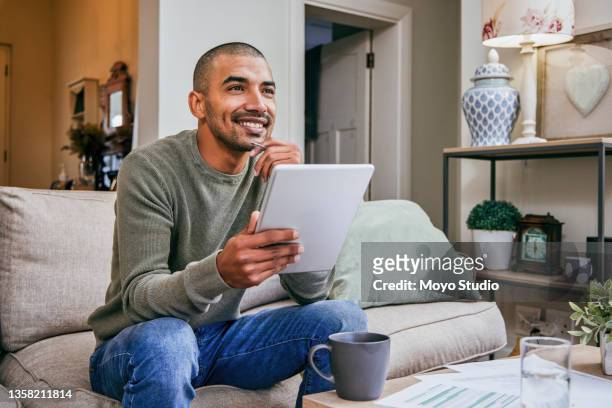 shot of a young man using his digital tablet while relaxing at home - bachelor apartment stock pictures, royalty-free photos & images