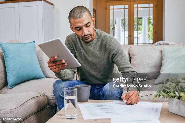 foto de un hombre llenando papeleo mientras usaba su tableta digital - form filling fotografías e imágenes de stock