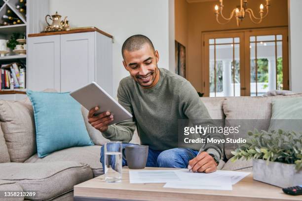 shot of a man filling out paperwork while using his digital tablet - form filling stock pictures, royalty-free photos & images
