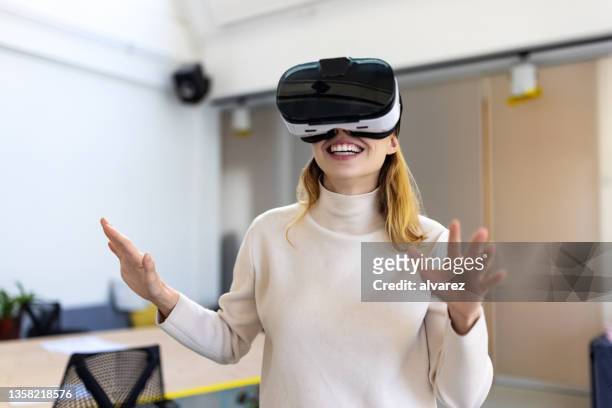 young businesswoman wearing vr headset to enter the metaverse in office - virtual reality stockfoto's en -beelden