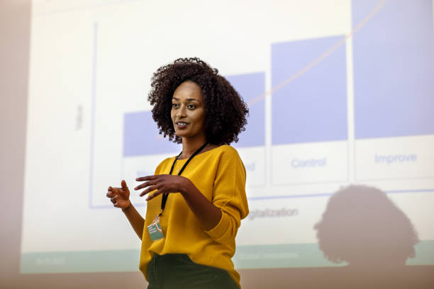 woman entrepreneur at seminar giving presentation - black woman presenting stock pictures, royalty-free photos & images