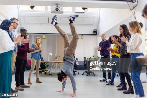 office staff celebrating a success at office with a wild handstand - fazer o pino imagens e fotografias de stock